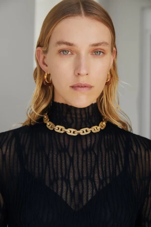 Model wearing a sheer black textured top, gold chain necklace, and tortoiseshell hoop earrings in Sydney