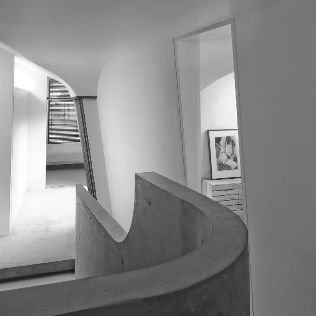 Black and white interior shot of a curved concrete railing and white walls, doors, and flooring in a modern architectural design.