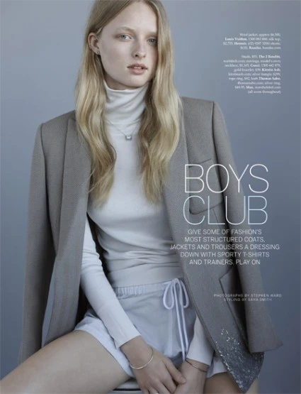 Fashion editorial shot of a woman in a blazer and shorts, posing in a studio with soft lighting. Neutral tones with readable text.