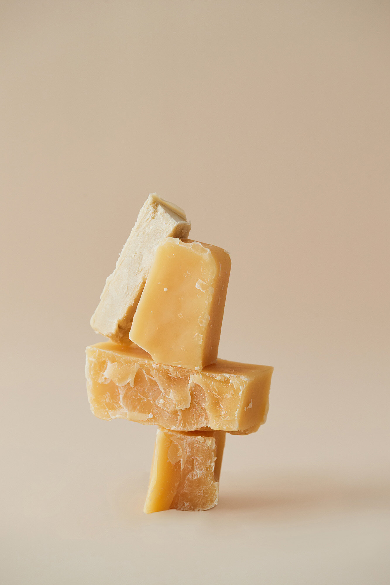 Stack of beige and white soaps with rough textures on a soft beige background, clean skincare products still life photography.