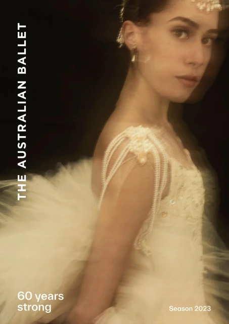 Portrait of a young ballerina wearing a pearl-adorned tutu, jewelry, and hairpiece against a dark background for a dance company ad.