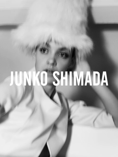 Black and white portrait of a woman wearing a furry hat and white jacket with JUNKO SHIMADA text overlayed on the image.