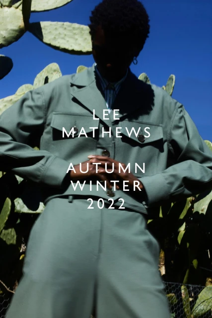 Woman in a sage green pantsuit poses outdoors near cactus plants. Fashion editorial image for Lee Mathews Autumn Winter 2022 collection.