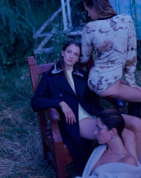 Three models posed outdoors in twilight with dark coat, patterned top, and cream shawl, styled by Bridie Gilbert