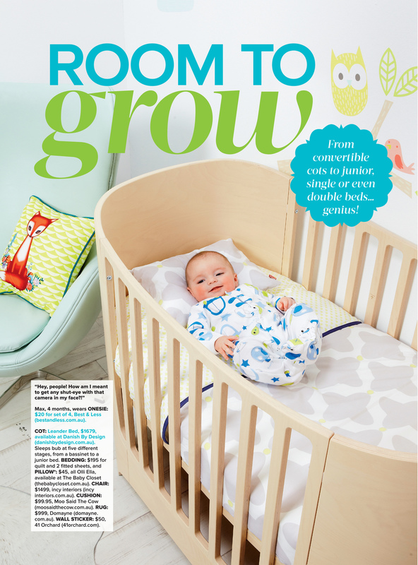 Infant lying in a light wood crib with bedding and an owl and bird decal on wall; soft blue chair with fox pillow in background.