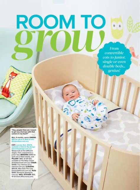 Infant lying in a light wood crib with bedding and an owl and bird decal on wall; soft blue chair with fox pillow in background.