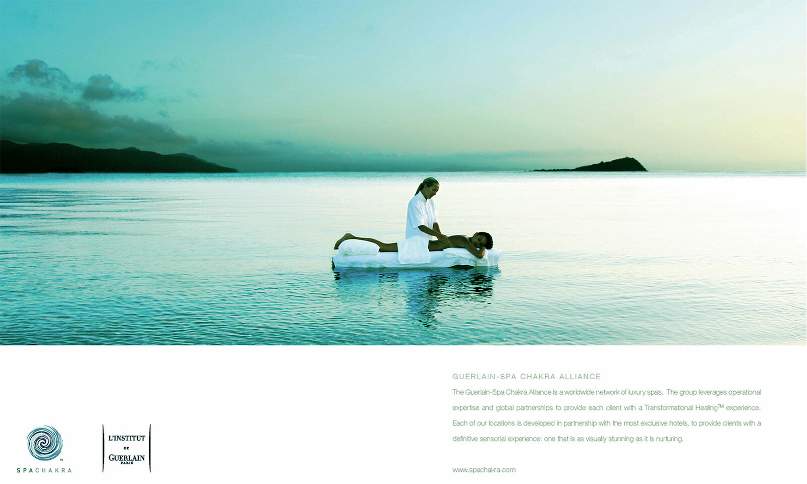 Woman giving a massage to a man on a floating platform in the ocean, with a calm sea and distant island in the background.