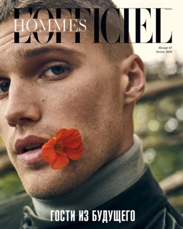 Close-up portrait of a man holding a bright orange flower between his lips, styled by Julianna Yao.