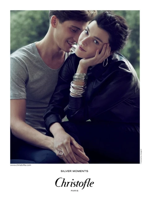 A stylish couple poses intimately in an outdoor setting, showcasing silver jewelry against a soft, natural backdrop with subtle lighting.
