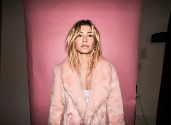 Portrait of Hailey Bieber wearing a pink fluffy coat against a pink seamless backdrop by photographer Mitch Hay