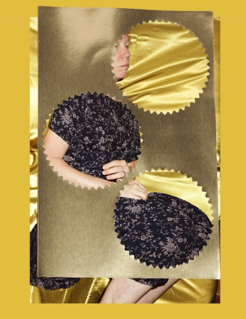 Conceptual portrait of a person partially visible through cutouts in a gold foil board, floral dress. Gold background. Art photography.