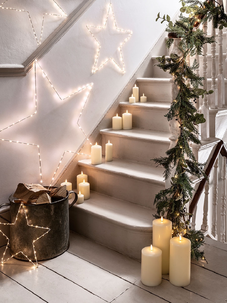 Cozy indoor staircase decorated with illuminated star ornaments, lit candles, and a garland, creating a warm, festive ambiance.