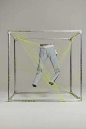Fashion shot of light wash jeans inside a square metal frame with fluorescent string creating a dynamic display against a neutral background.