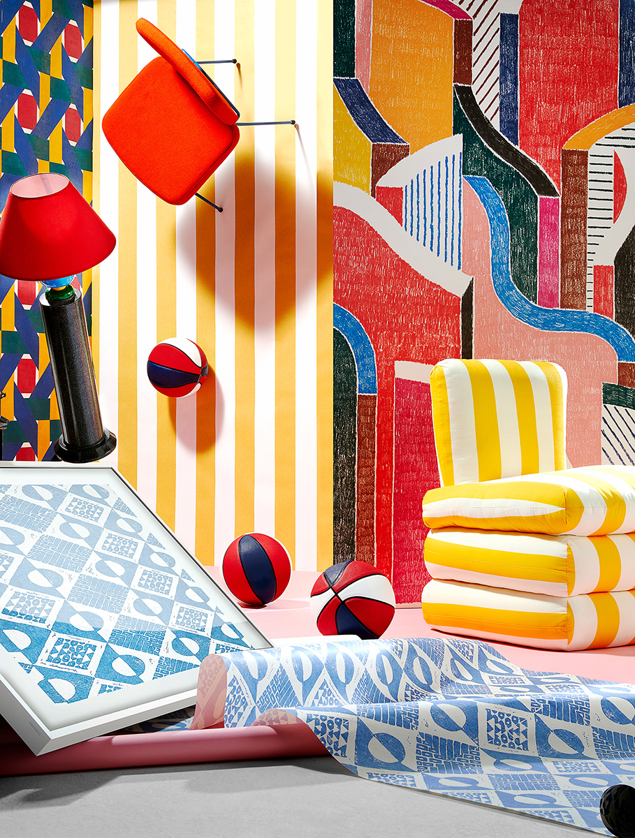 Still life composition with a floating orange chair, yellow striped cushions, balls, and patterned fabrics against colorful backgrounds.