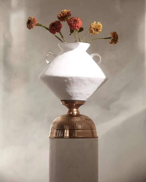 Still life photograph of flowers in a white vase on a pedestal, featuring a soft color palette and elegant composition. 