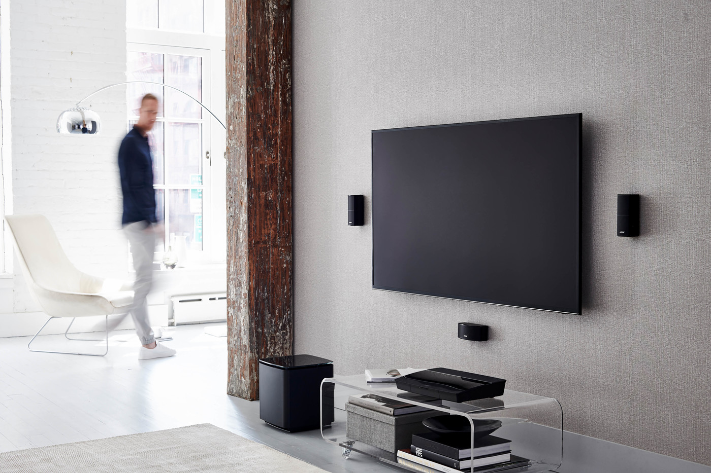 Modern living room interior with a large flat-screen TV mounted on the wall, complemented by sleek speakers and a minimalist aesthetic.