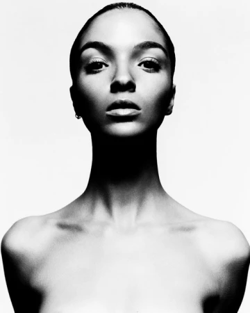 Monochrome portrait of a woman with her hair pulled back against a stark white background by Todd Barry