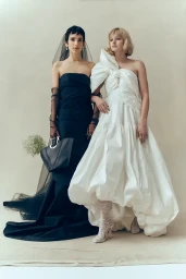 Two female models posing against a neutral backdrop wearing formal black and white gowns, produced in Sydney by Laura Midalia.