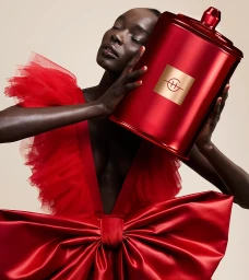 Black woman in a red tulle dress holding a large red canister with a square gold logo in Sydney by producer Laura Midalia