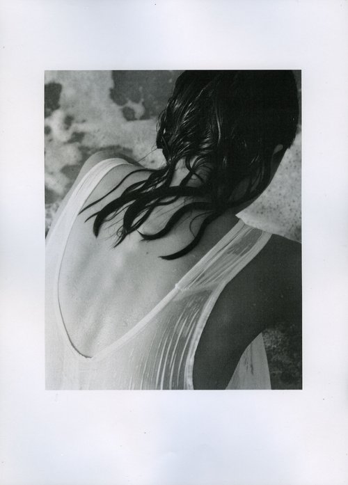 Back view of a woman with wet dark hair and a white translucent dress. Black and white portrait.