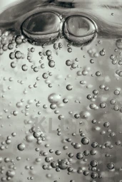 Macro close-up shot of rising bubbles suspended in clear liquid with faint text visible