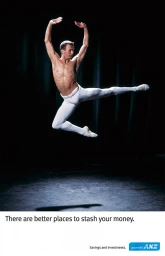 Male ballet dancer leaping mid-air wearing white tights against a dark theatrical backdrop by Stuart Crossett