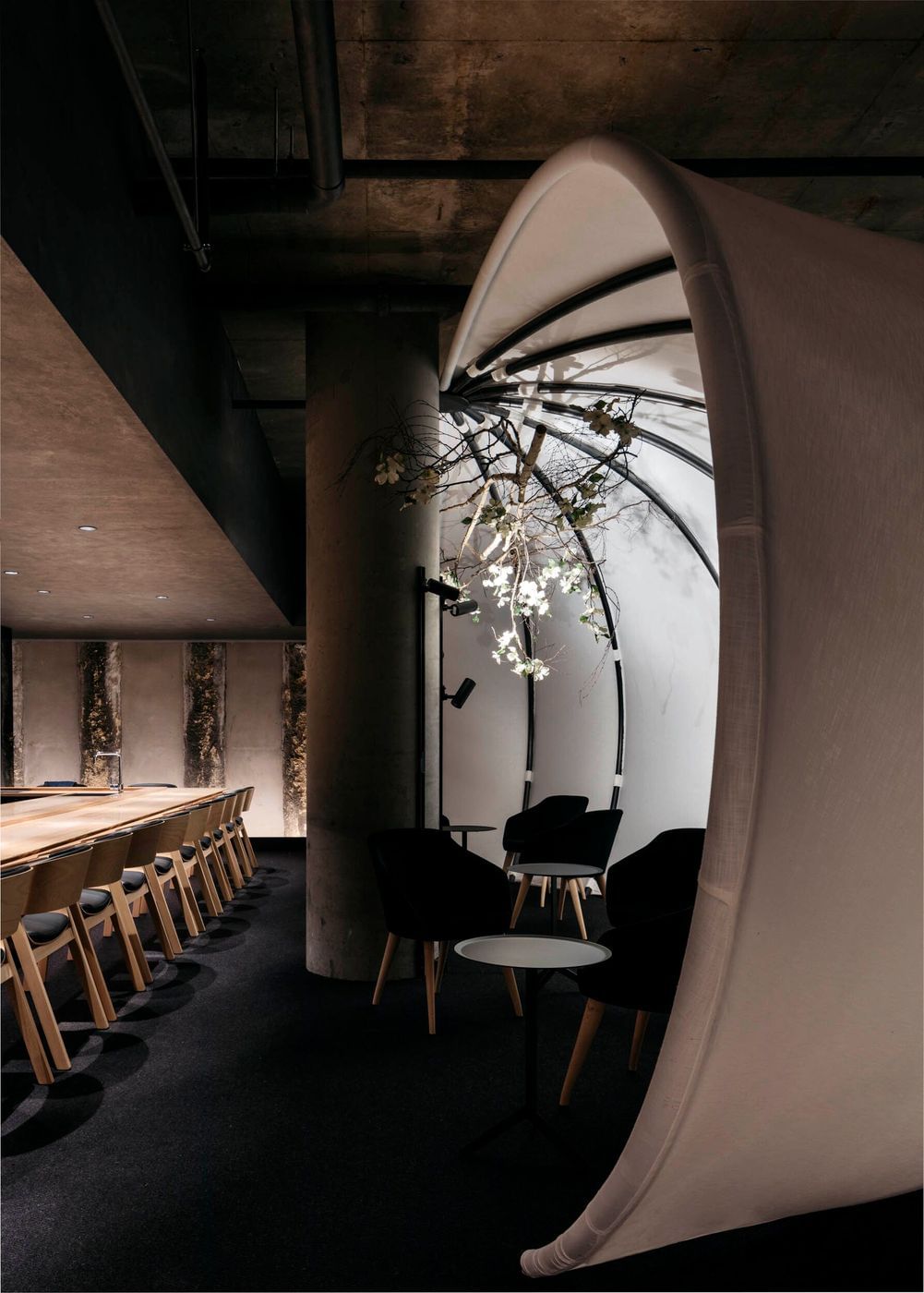 Interior design featuring a lounge area with modern chairs and a round table, set against a backdrop of a long conference table.