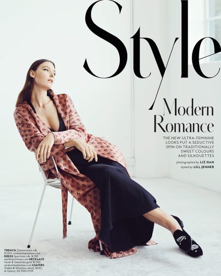 Fashion magazine cover featuring a woman in a pink patterned robe and black dress, seated on a silver chair in a studio setting.