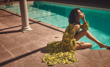 Woman in yellow patterned dress seated by a blue swimming pool in Sydney styled by Lill Jenner