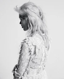 Profile view of a woman with blonde hair wearing a white lace dress styled by Lill Jenner against a seamless white background