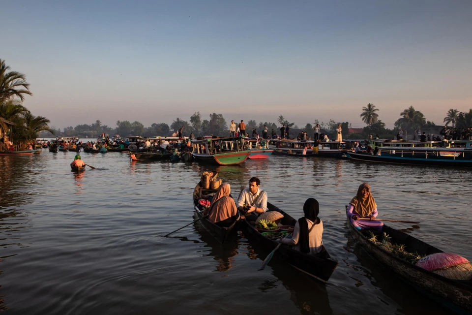 Early morning scene captures boats filled with people in a bustling floating market in Southeast Asia, highlighting local culture.