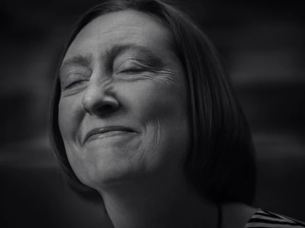Close-up portrait of a woman with her eyes closed and a subtle smile, captured in monochrome by photographer Jez Smith.