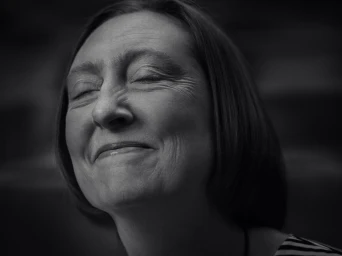 Close-up portrait of a woman with her eyes closed and a subtle smile, captured in monochrome by photographer Jez Smith.
