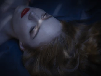 Close-up portrait of a woman with red lipstick lying down under dramatic lighting by Jez Smith in Sydney