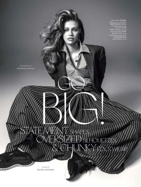 Editorial fashion shot featuring a stylish woman in a blazer and striped skirt, posing in a studio with bold text overlay.