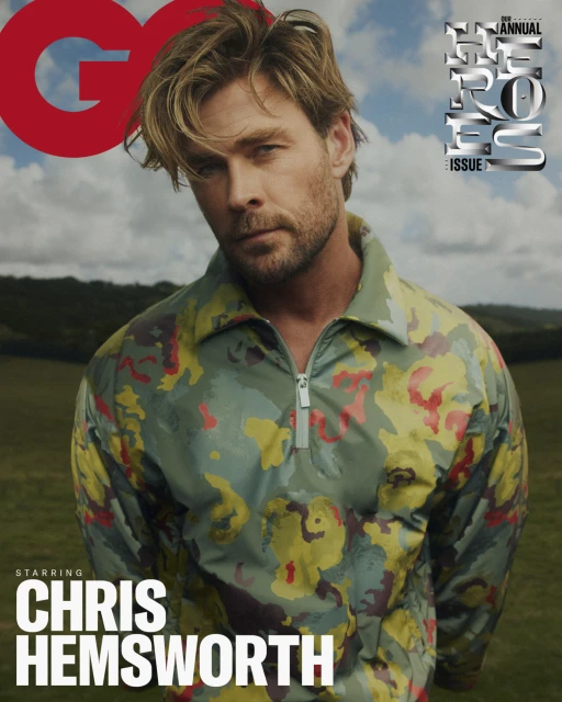 GQ cover featuring Chris Hemsworth in a patterned jacket, set against a blurred outdoor backdrop with sky and green landscape.