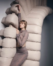Model with bangs posing against a large modular cream tufted sofa in Sydney by make-up artist Stoj Bulic