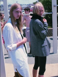 Two blond female models styled by Nicki Colbran outdoors in Sydney, wearing a white shirt and grey blazer.