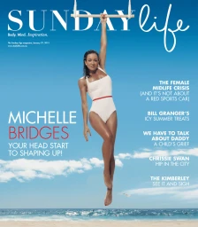 Woman in white one-piece swimsuit hanging from a trapeze bar against a bright blue sky and ocean background