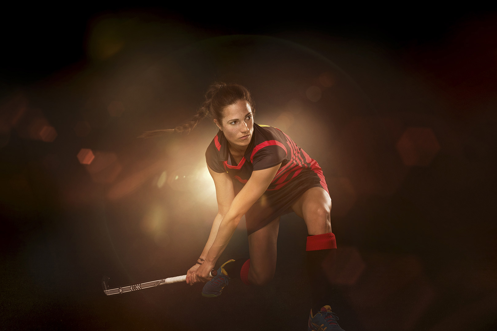 Female athlete in action: Woman in sports uniform skillfully plays field hockey, demonstrating agility and focus against a dark background.
