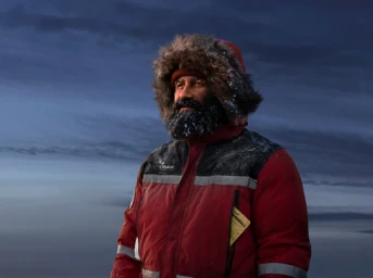 Man with heavy beard wearing a red parka with fur hood against a stormy sky background