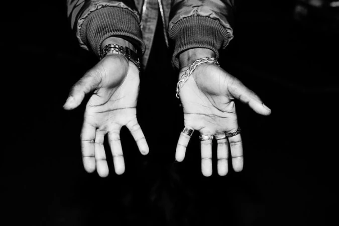 Close-up of open hands with rings and bracelets against a dark background, photographed by Bas&Chris.