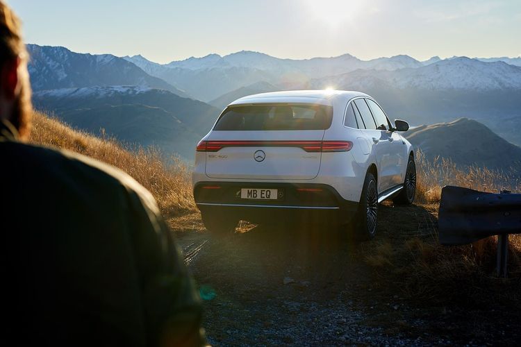 Rear view of a white electric SUV parked on a mountain track at sunset, photographed by Bas and Chris.
