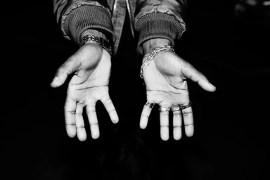 Close-up of open hands with rings and bracelets against a dark background, photographed by Bas&Chris.