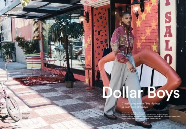 A man walking on a tiled sidewalk past a pink storefront with a large inflatable lips sculpture and potted palm.