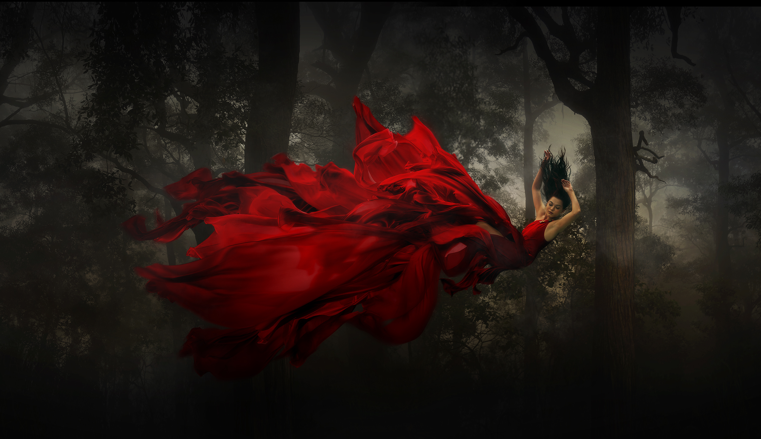 Woman in flowing red dress appears to be falling in a dark forest. Fantasy art, fairytale, dark mood, surreal, and dramatic lighting.