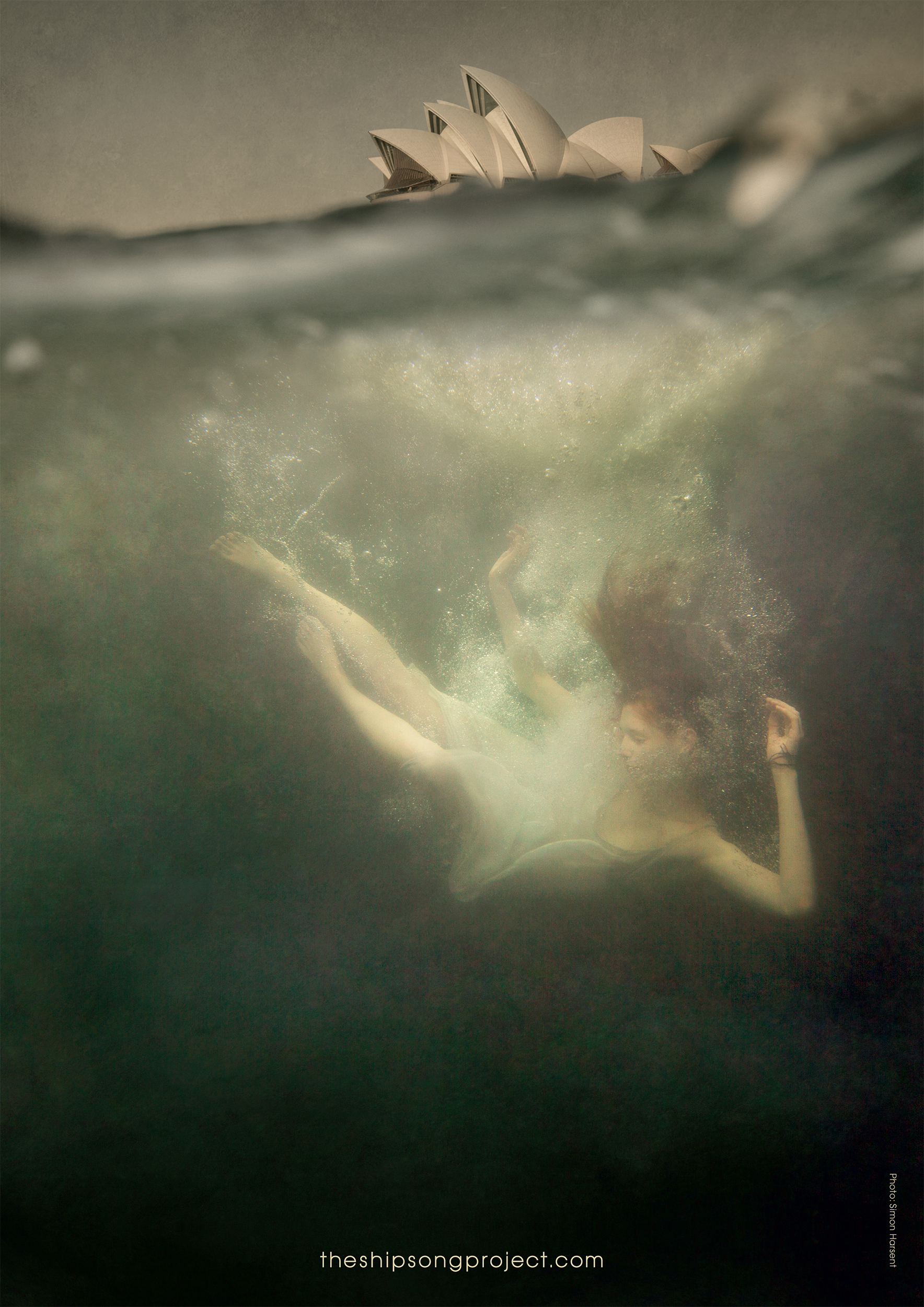 Woman in a white dress swims underwater, with the Sydney Opera House visible above the water line. Bubbles and filtered light enhance the ethereal scene.