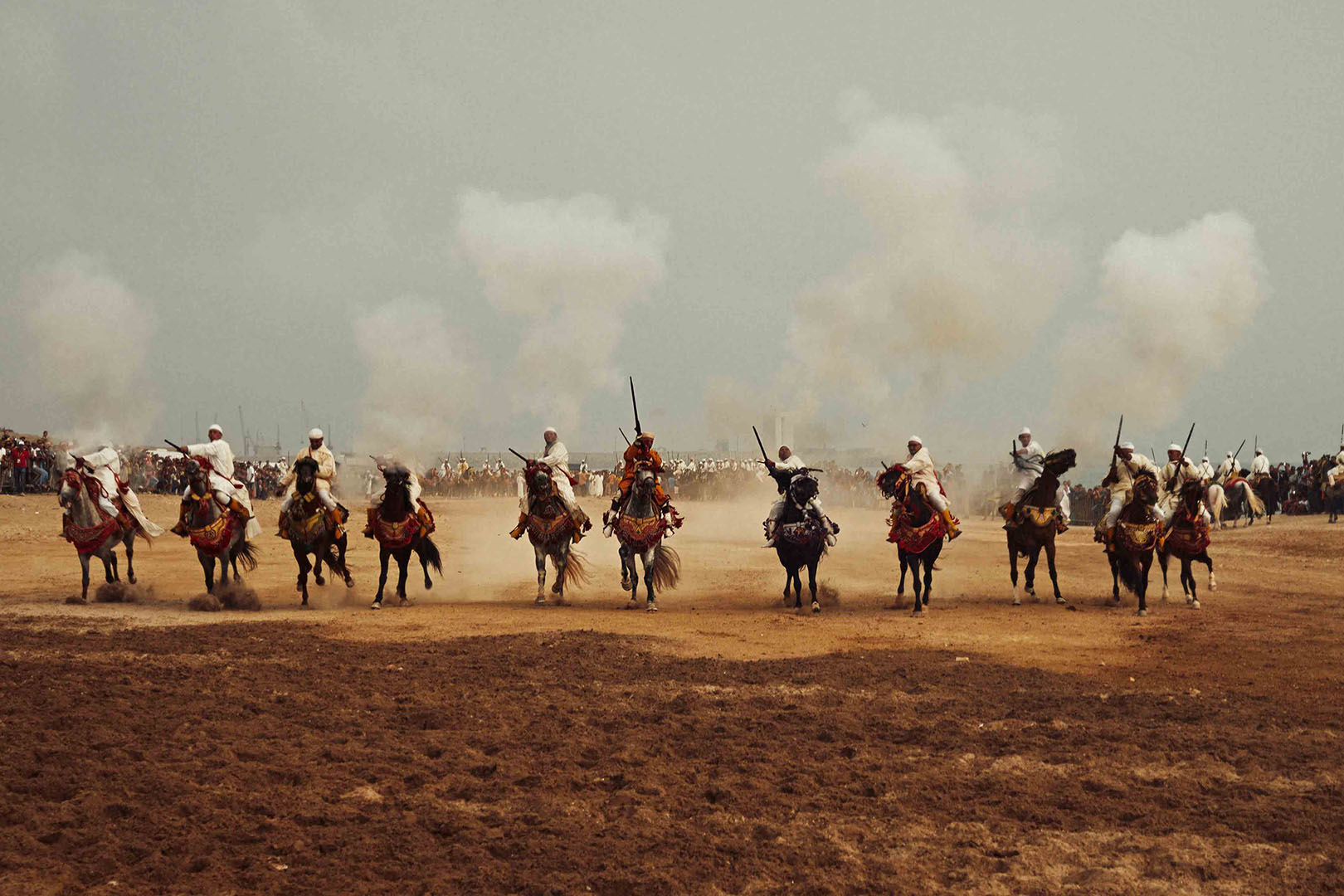 Fantasia equestrian performance featuring riders on horseback in traditional Moroccan attire during a cultural festival event.