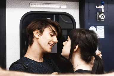 Young man and woman looking closely at each other inside a train cabin by photographer Karima Asaad