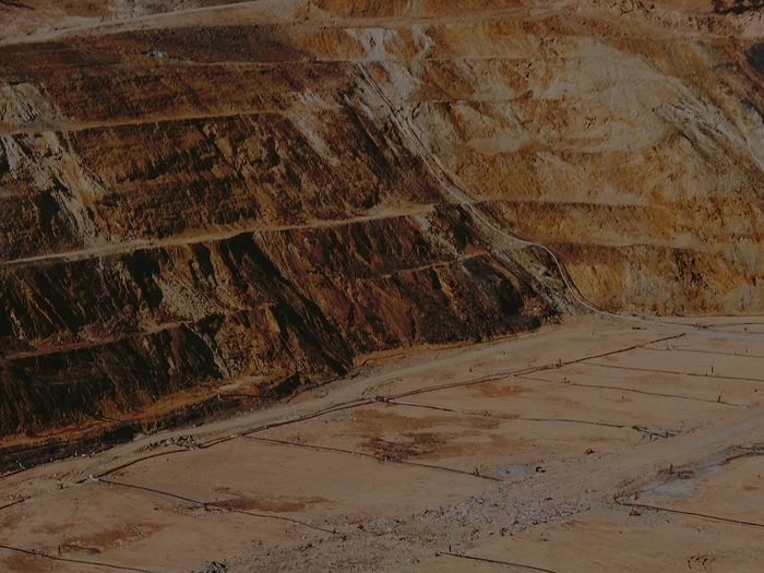 Aerial view of a large open-pit mine with terraced earth benches and expansive dry excavation floor